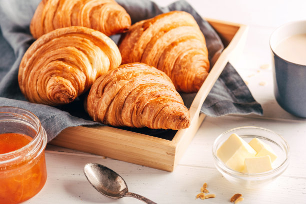 白色的木桌上放着新鲜的羊角面包、果酱和咖啡。图片下载