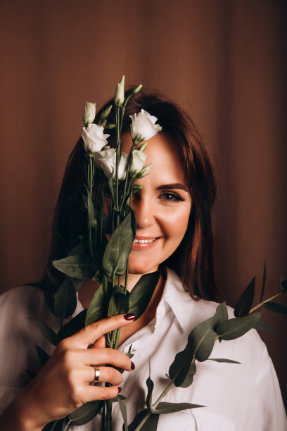 一个年轻美丽的女孩的肖像在白衬衫，谁在她的手握一朵杜鹃花图片下载