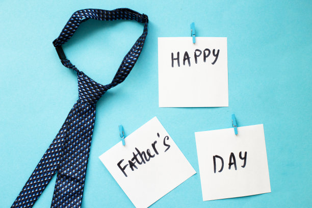 蓝色底系领带的晒衣夹上贴着“父亲节快乐”的贴纸。图片下载