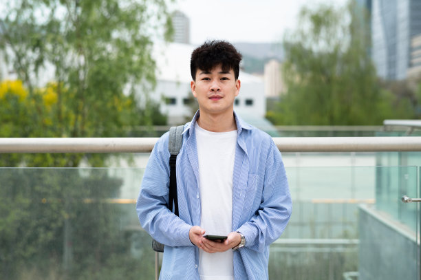 亚洲年轻英俊的大学生在城市街道图片下载