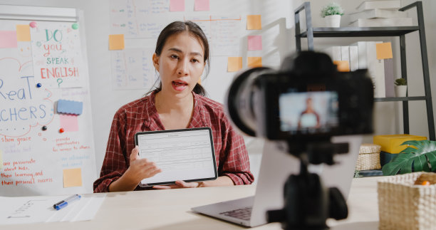 年轻的女教师通过家里的摄像头视频授课。图片下载