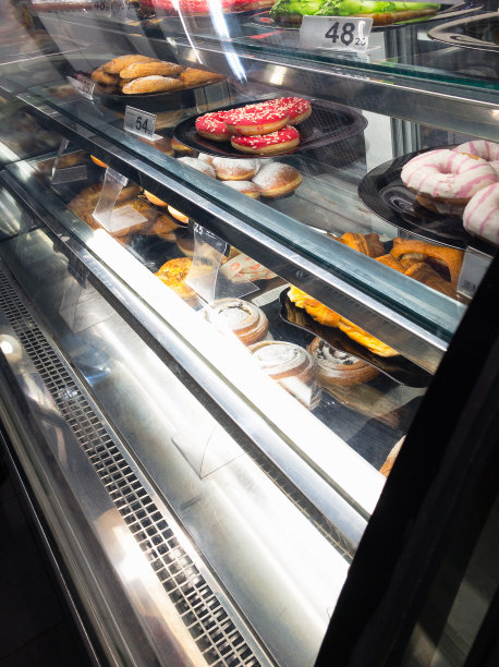 蛋糕和甜甜圈在咖啡店冷藏烘焙盒出售图片下载