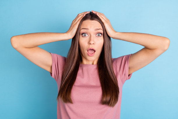 照片害怕不开心恐慌的年轻女子，手握着头担心孤立在蓝色的背景图片下载