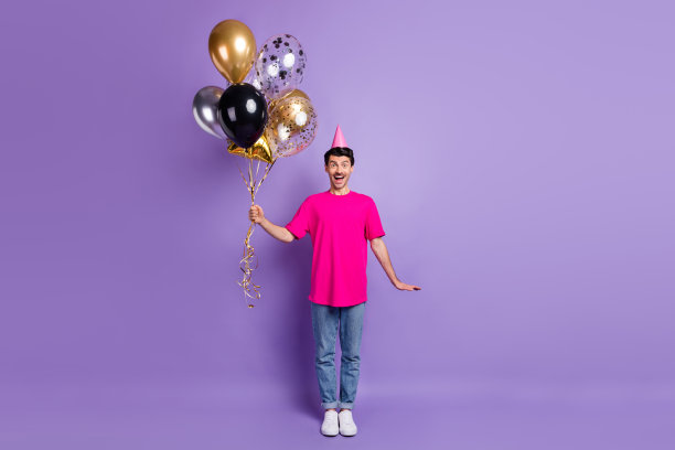 惊讶的大帅哥手拿气球张开嘴微笑孤立在紫罗兰色背景的照片图片下载