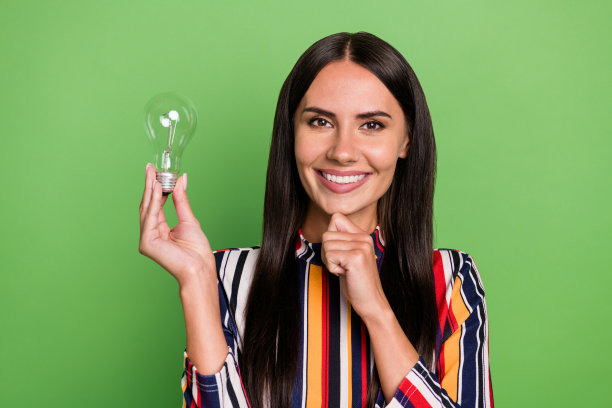 迷人的性格开朗的女孩手持灯泡的肖像线索猜测决定孤立在绿色粉彩背景图片下载