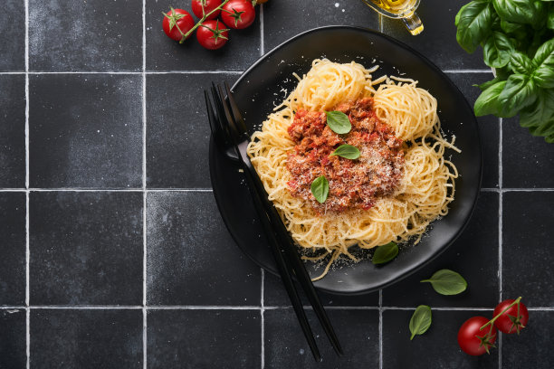 意大利面，肉丸加番茄酱，罗勒和帕尔马干酪，黑色石头或混凝土背景。传统的意大利菜和菜肴。带有拷贝空间的俯视图。图片下载