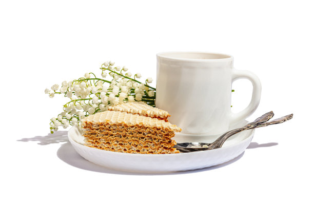 一杯咖啡和华夫饼被孤立在白色背景上。香甜的甜点配上百合谷花束图片下载