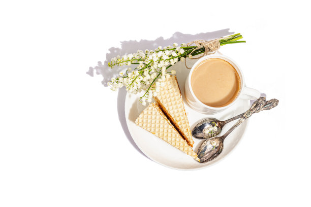 一杯咖啡和华夫饼被孤立在白色背景上。香甜的甜点配上百合谷花束图片下载