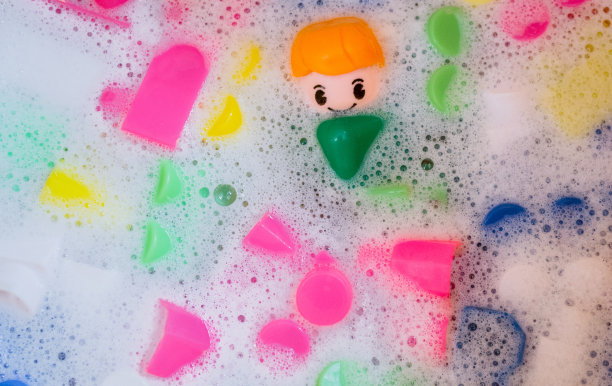 清洗儿童玩具，塑料积木和小雕像。一个微笑的小家伙和五颜六色的立方体漂浮在泡沫的水中。卫生的观念，清洁的观念。安全性和消毒图片下载