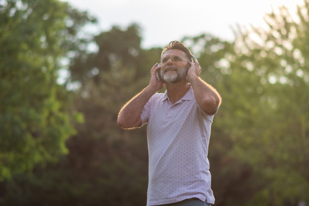 快乐成熟的大胡子听音乐。图片下载