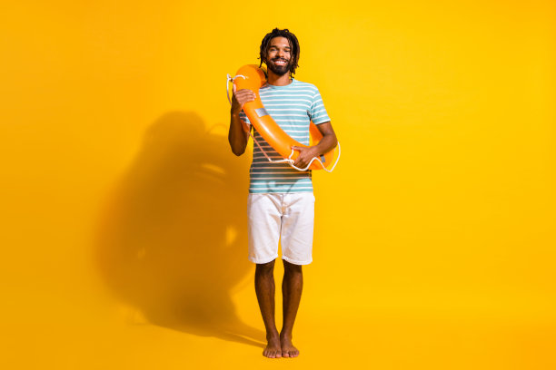 照片肖像全身视图可靠的黑色皮肤家伙海岸警卫队穿着救生圈孤立在生动的黄色背景图片下载