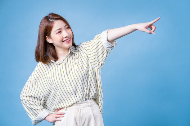 年轻的亚洲女孩在蓝色背景摆拍的图像图片下载