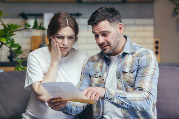 特写照片已婚夫妇丈夫和孕妇收到银行的信，沮丧和不安坐在沙发上图片下载