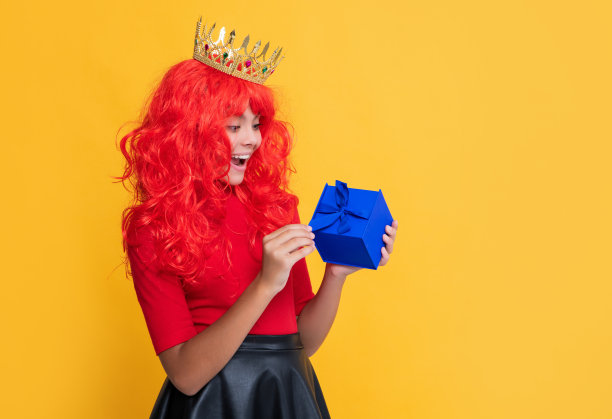 震惊的孩子在皇冠上的礼物盒子上的黄色背景图片下载