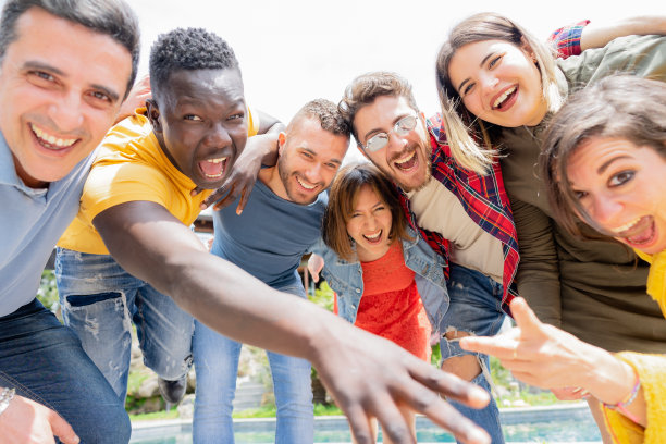 一群朋友看着镜头，在有游泳池和花园的大别墅里开玩笑——有趣的人，不同年龄的人享受在假期图片下载