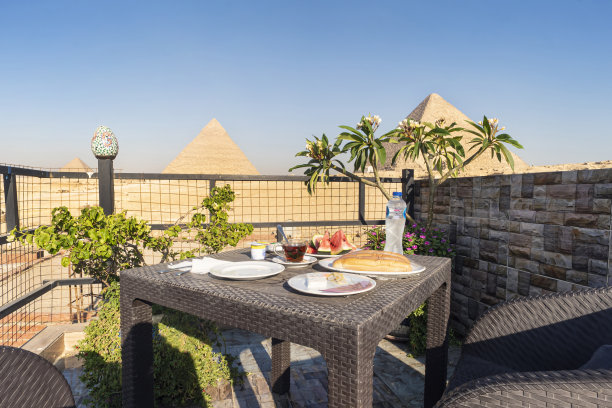 旅行者的早餐：在户外餐厅的餐桌上欣赏吉萨大金字塔的绝美景色（埃及开罗）图片下载