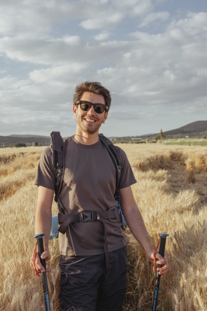 英俊的年轻人在麦田里徒步旅行图片下载
