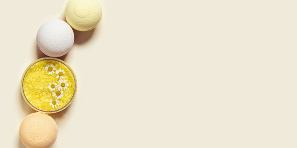 俯视图浴弹和海盐，草药洋甘菊提取物，水疗产品关闭。天然美容护理和身体护理化妆品，中草药，米色背景，宽横幅图片下载