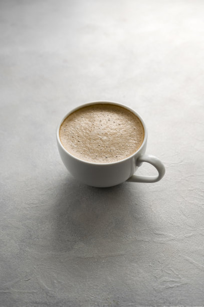 咖啡杯在纹理灰色背景。生活方式照片与自然光线。简约风格的咖啡和牛奶泡沫杯。图片下载