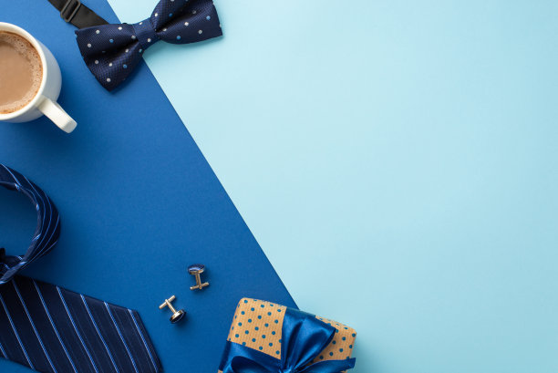 父亲节的概念。顶视图照片的波点礼盒与丝带蝴蝶结杯咖啡袖扣蓝色领结和领带双色蓝色背景与空白图片下载