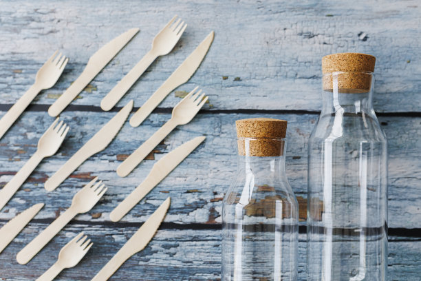 浅蓝色木制背景上的环保餐具平面组合。牛皮纸盘子和木制餐具。可回收的纸制品，零浪费的理念。有选择性的重点图片下载