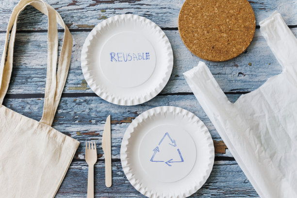 浅蓝色木制背景上的环保餐具平面组合。牛皮纸盘子和木制餐具。可回收的纸制品，零浪费的理念。有选择性的重点图片下载