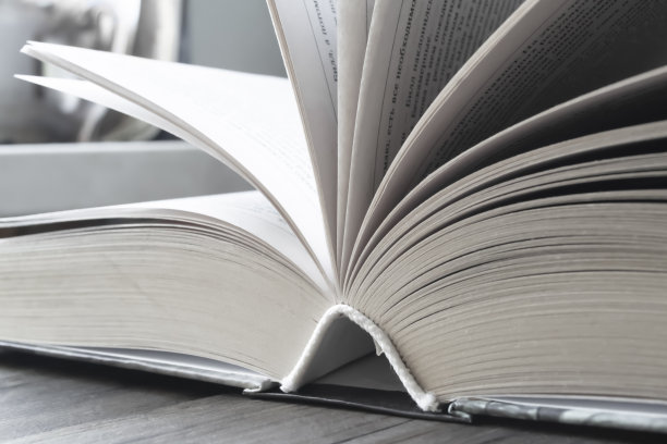 桌子上的那本厚书是打开的。打开书。这本书的书页向不同的方向伸出。照片与柔和的颜色。图片下载