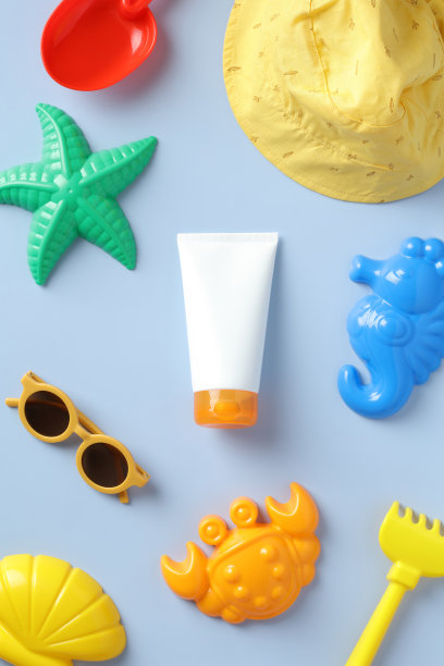 婴儿防晒概念。儿童防晒乳管，太阳镜，巴拿马草帽，蓝色背景上的沙模。平铺，俯视图。图片下载