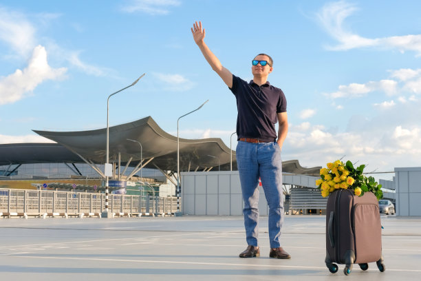 一个带着行李的男人在机场停车场迎接旅客。出差、休假图片下载