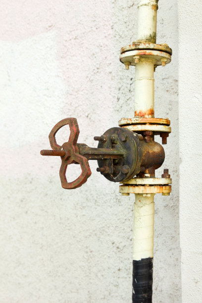 白色墙壁背景上生锈的管道阀门。图片下载