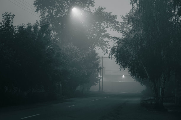 在一个大雾弥漫的夜晚，街道被LED路灯照亮图片下载
