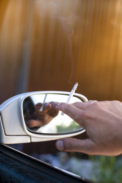 在汽车里吸烟的危险出现在后视镜的背景上，前后背景用散景效果模糊图片下载