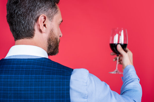 成熟男士侍酒师或调酒师品尝一杯红酒，后视图选择性聚焦，奢华畅饮图片下载