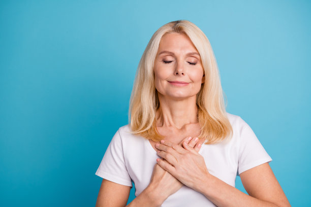 平静祥和的照片老妇人把她的手胸前穿好看的衣服隔离在蓝色的背景图片下载