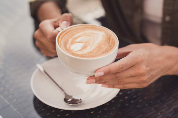 裁剪概念照片肖像的女人拿着咖啡杯错综复杂的拉花艺术图片下载