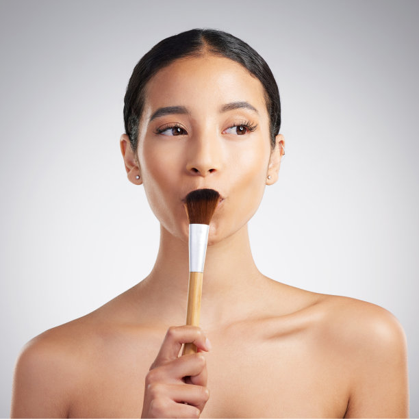 一个美丽的混血女人摆着化妆刷在一个娇生惯养的例行。西班牙模型拿着一个轮廓刷对灰色的copyspace背景图片下载