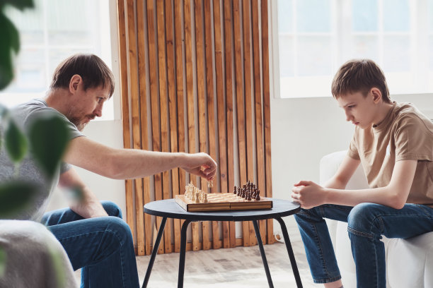 父子俩在家里下棋。家庭休闲一起图片下载