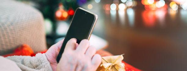 近距离拍摄圣诞假期使用手机的老人的手。图片下载