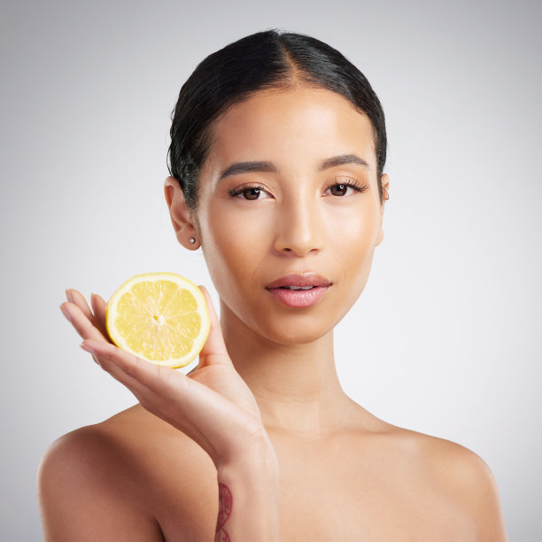 工作室肖像一个美丽的年轻混合种族的女人拿着柠檬。西班牙裔模特在灰色的文案背景下用柠檬提亮皮肤图片下载