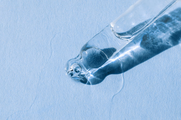 带液体透明质酸的移液器，单色蓝色背景。化妆品和保健概念特写图片下载