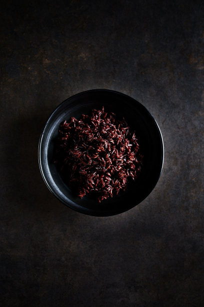 一碗煮熟的黑米在黑色的石头背景。前视图。本空间图片下载