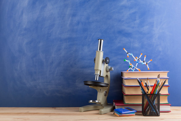 教育和科学概念——书，分子模型和显微镜放在礼堂的桌子上，黑板作为背景。图片下载