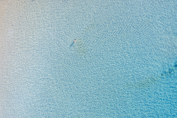 男子游泳在透明的蓝绿色海水空中无人机的看法。夏日艳阳天，希腊图片下载