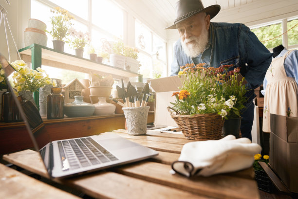上了年纪的男性花店老板在工作时使用笔记本电脑图片下载