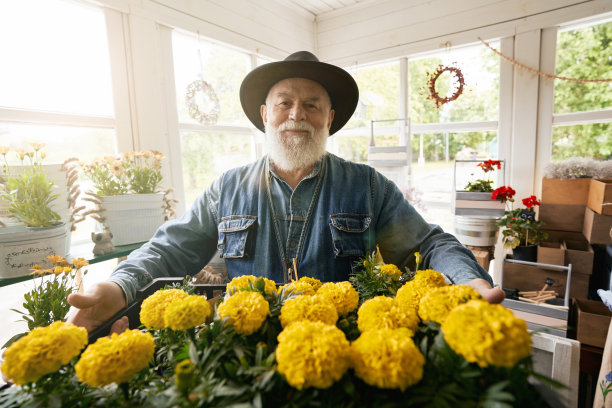 快乐的花商在自己的店铺里展示出售的黄色花朵图片下载