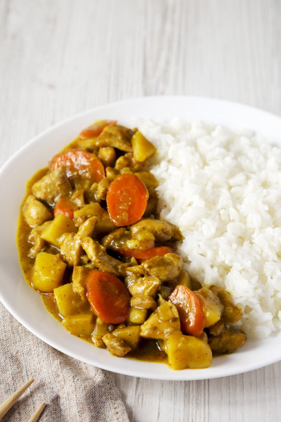 自制的日式咖喱鸡放在白色的盘子上，白色的木制背景，侧视图。空间的文本。图片下载