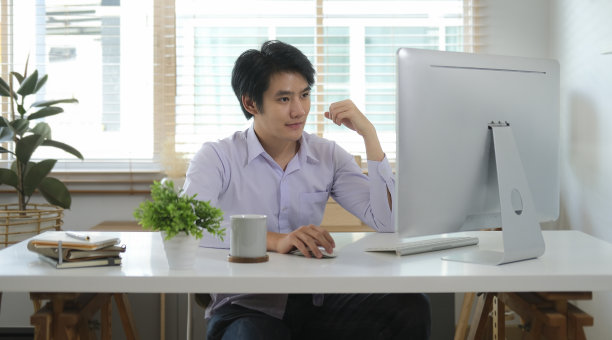 英俊的年轻商人在家里用电脑办公。图片下载