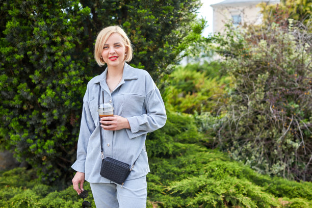 时髦的年轻金发女郎在城市里走来走去，喝着冷饮。图片下载