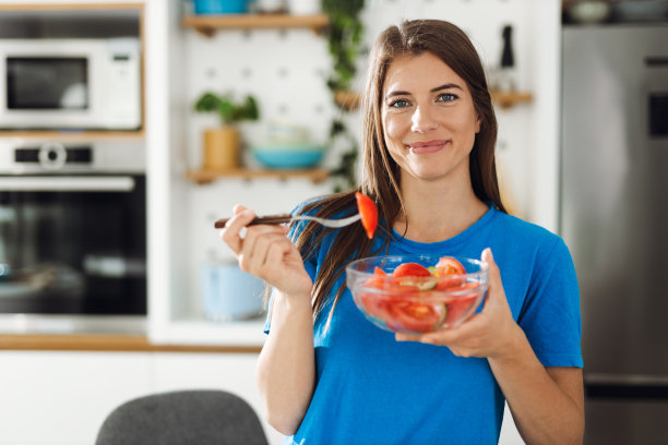 快乐的女人在厨房里端着一碗沙拉图片下载
