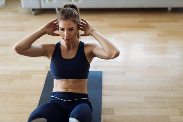 年轻女子在家地板上做仰卧起坐图片下载